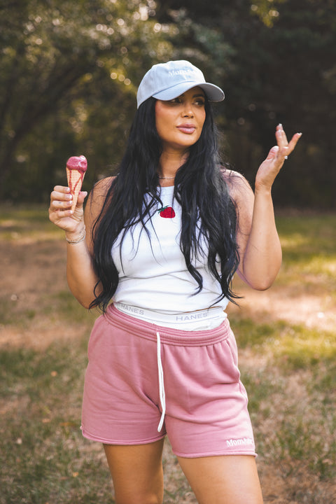 Woman in pink shorts and white tank top holding ice cream cones outdoors