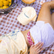 Person lying on a checkered blanket with a pie, lemons, and a plush toy.