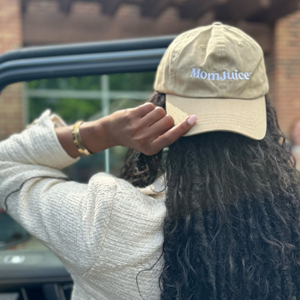 Black Woman with locs wearing Mom Juice hat in sand