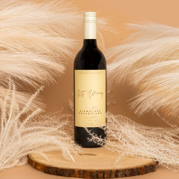 Wine bottle on a wooden coaster with decorative pampas grass against a beige background