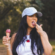 Woman eating ice cream outdoors wearing a cap and Hanes shirt