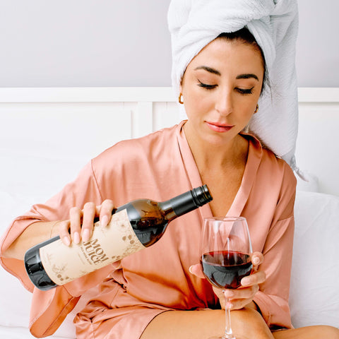 Woman in robe pouring Mom Juice Wine