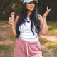 Woman in pink shorts and white tank top holding ice cream cones outdoors